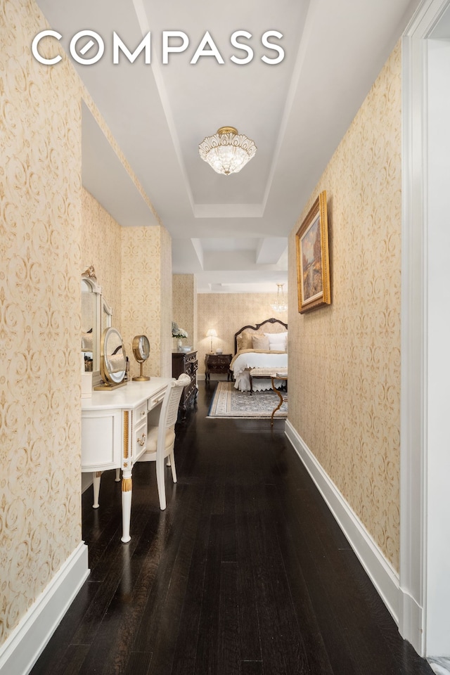 hallway featuring baseboards, wood finished floors, and wallpapered walls