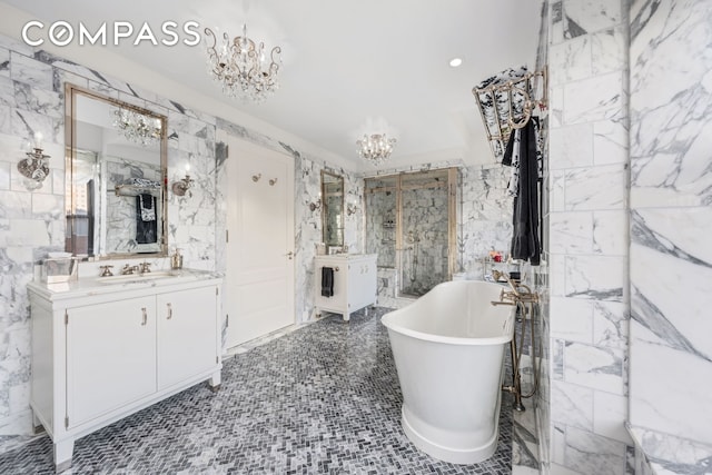 bathroom featuring tile walls, a soaking tub, vanity, and an inviting chandelier