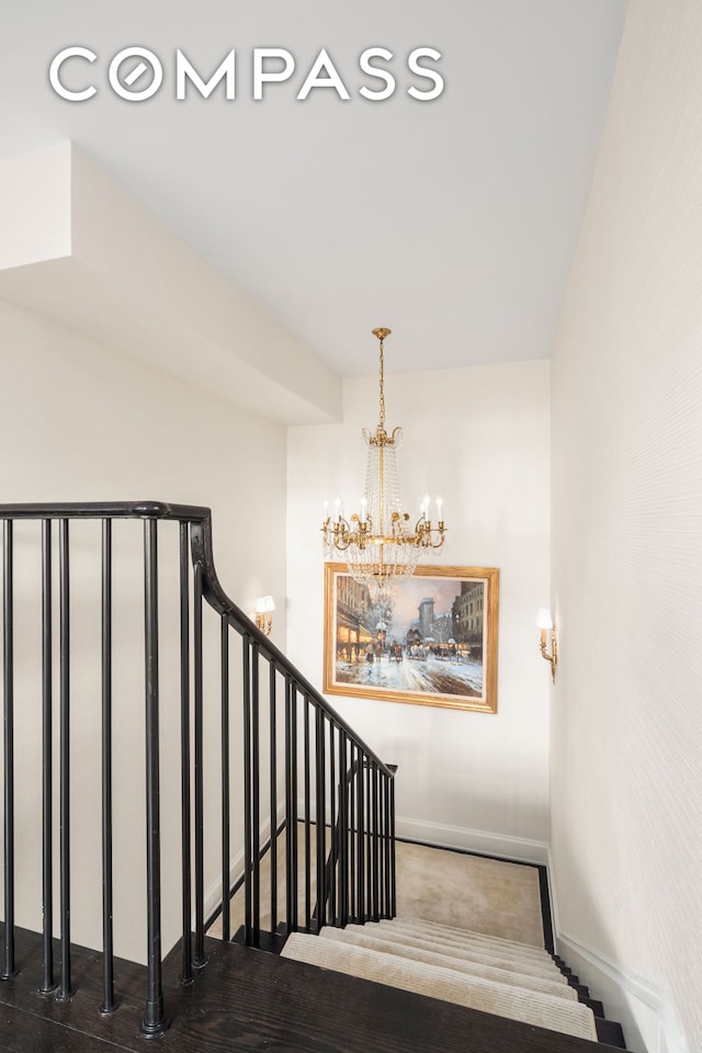 staircase with an inviting chandelier and baseboards