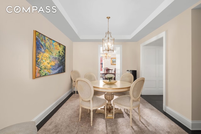 dining room with a notable chandelier, a raised ceiling, and baseboards