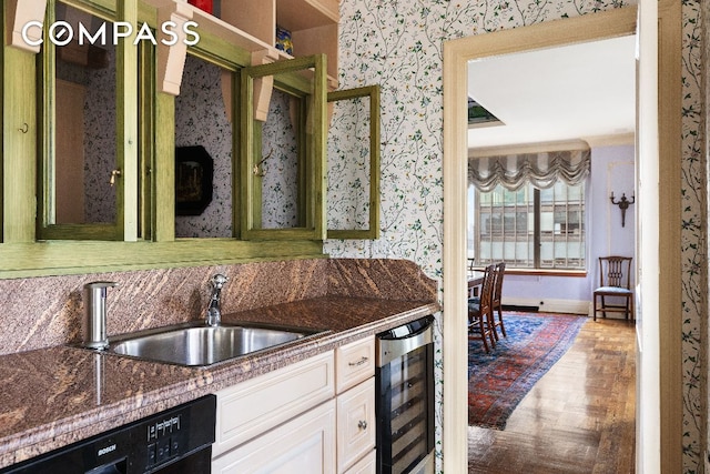 kitchen featuring black dishwasher, white cabinetry, a sink, beverage cooler, and wallpapered walls