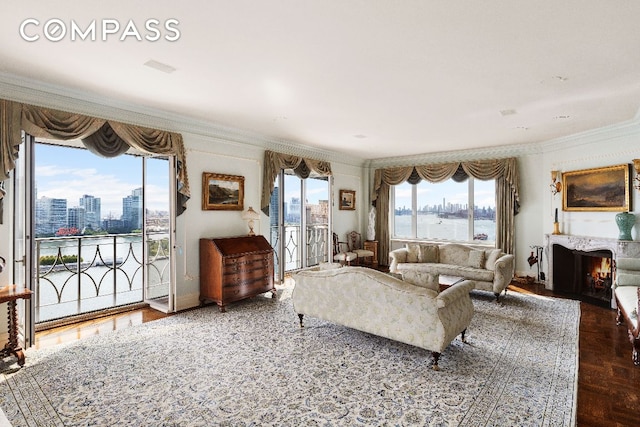 living room with a view of city, a lit fireplace, a water view, and crown molding