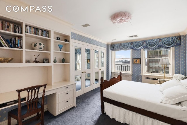 bedroom featuring visible vents, dark colored carpet, built in desk, radiator heating unit, and wallpapered walls