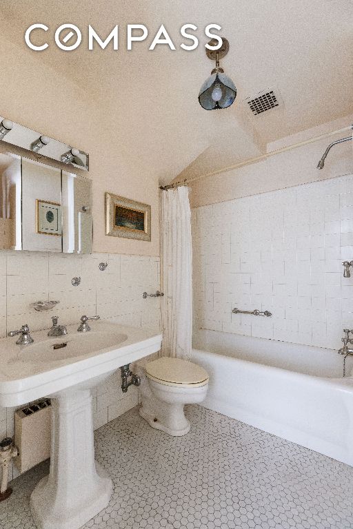 full bathroom featuring toilet, shower / tub combo, visible vents, tile walls, and tile patterned floors