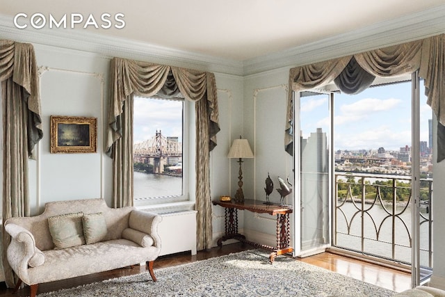 living area featuring a view of city, ornamental molding, and wood finished floors