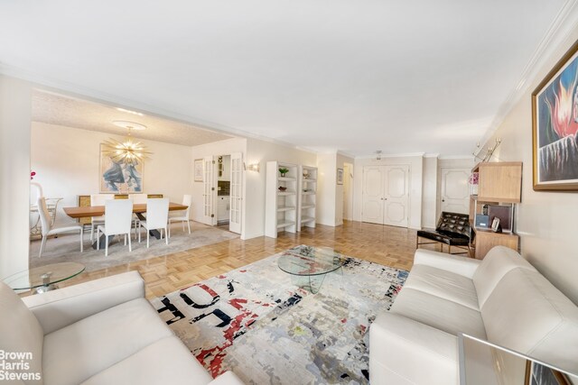 living room featuring light parquet floors, ornamental molding, and a notable chandelier