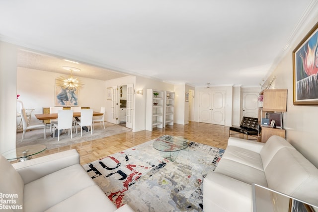 living area featuring baseboards, a chandelier, and crown molding