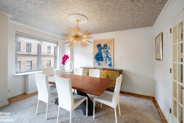 dining area with wood finished floors, crown molding, baseboards, and an inviting chandelier