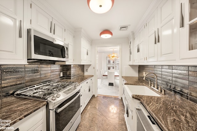 kitchen featuring appliances with stainless steel finishes, light marble finish floors, white cabinetry, and a sink