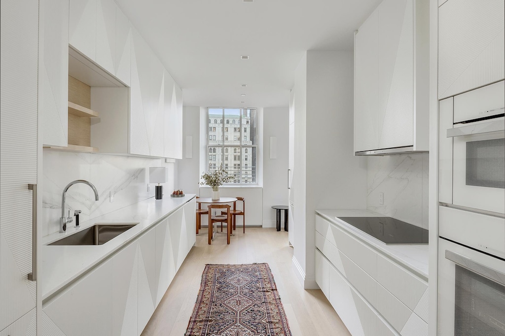 kitchen with a sink, decorative backsplash, modern cabinets, and white oven