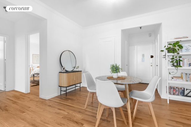 dining space featuring light wood-type flooring, ornamental molding, and baseboards