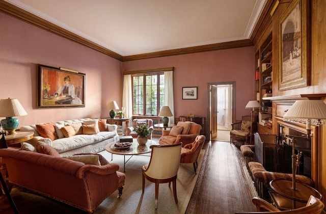 living room featuring dark wood-type flooring, ornamental molding, a high end fireplace, and built in features