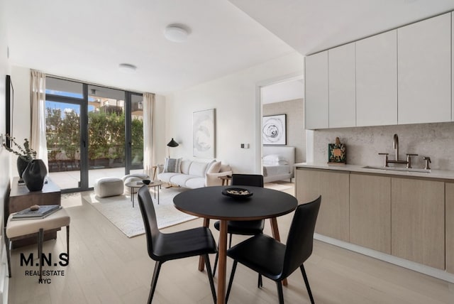 dining room with a wall of windows, light hardwood / wood-style flooring, and sink