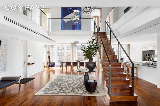 foyer entrance with a chandelier, stairway, a towering ceiling, and wood finished floors