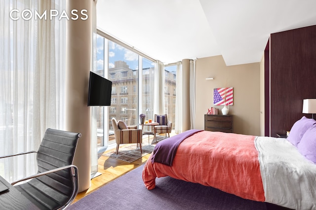 bedroom with expansive windows and wood finished floors