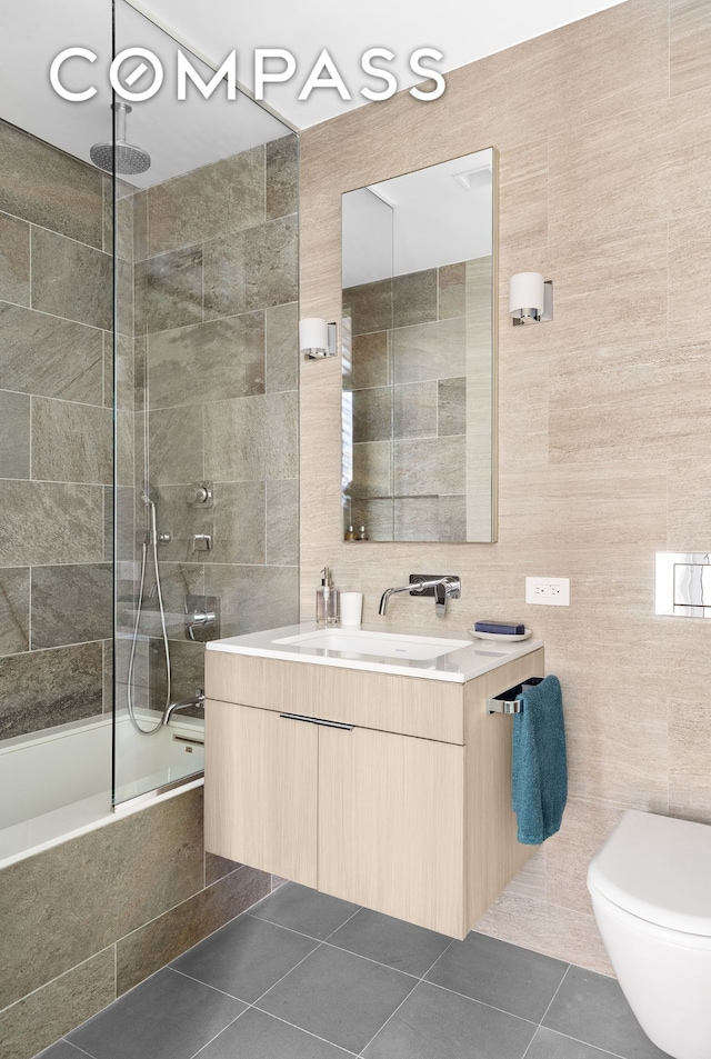 bathroom featuring toilet, tile patterned flooring, tile walls, and a combined bath / shower with rainfall shower