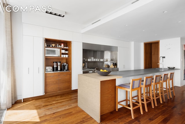 bar featuring a sink, wood finished floors, and visible vents