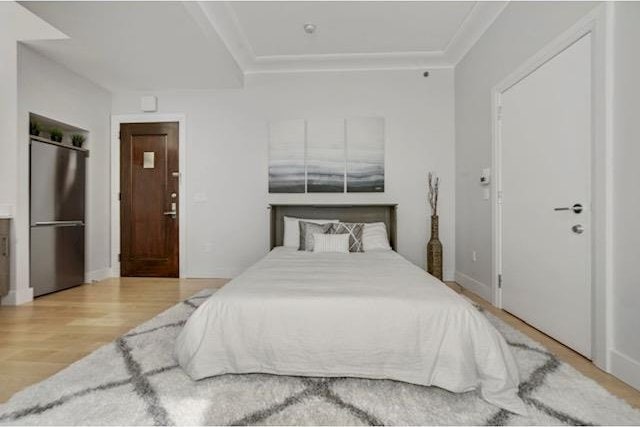 bedroom featuring wood finished floors and fridge