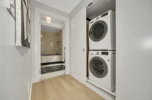 laundry room featuring laundry area, stacked washing maching and dryer, and wood finished floors