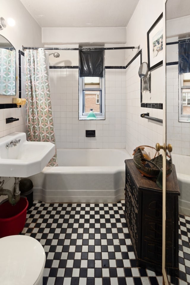 bathroom with tile walls, toilet, tile patterned floors, and shower / tub combo