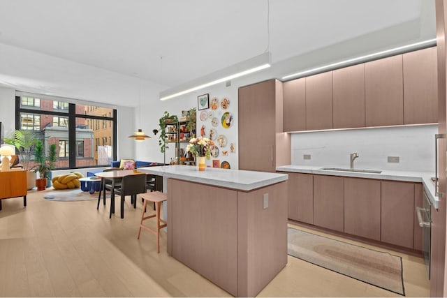 kitchen featuring sink, a center island, a breakfast bar, and light wood-type flooring