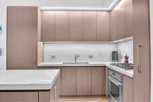 kitchen featuring backsplash, sink, light stone countertops, light brown cabinets, and stainless steel appliances