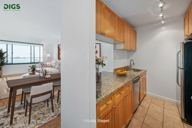 kitchen featuring sink, light tile patterned flooring, appliances with stainless steel finishes, track lighting, and light stone counters