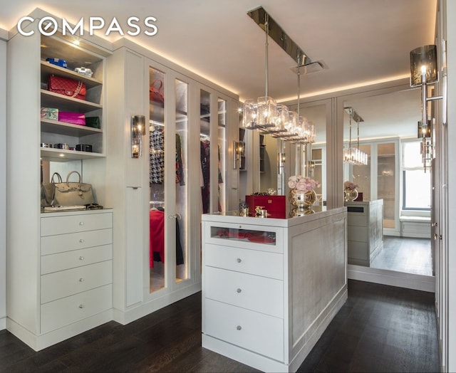 walk in closet featuring dark wood-style flooring and a notable chandelier