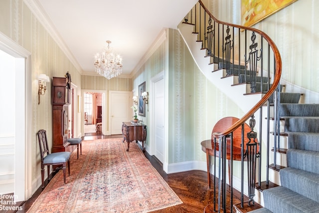 entryway featuring stairway, baseboards, wallpapered walls, ornamental molding, and a chandelier