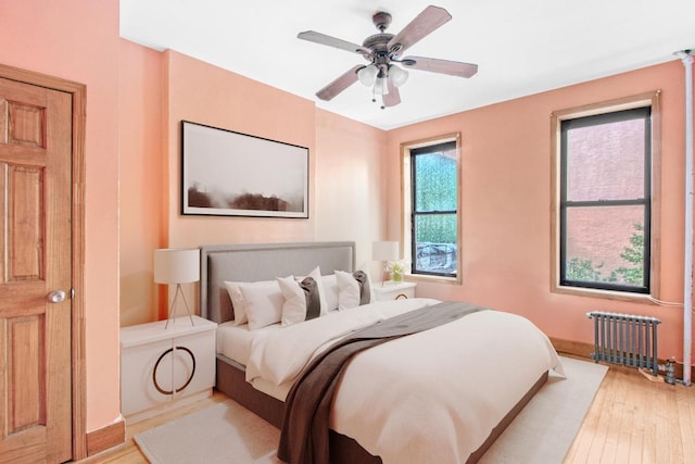 bedroom with ceiling fan, radiator, and light hardwood / wood-style flooring