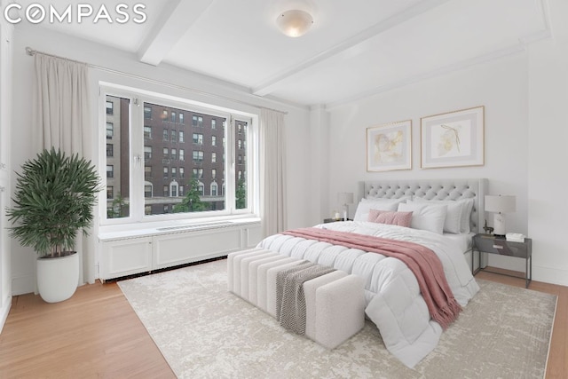 bedroom featuring light hardwood / wood-style floors and beam ceiling