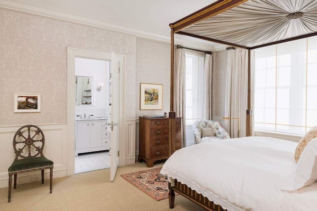 bedroom featuring crown molding, a decorative wall, ensuite bath, light carpet, and wallpapered walls
