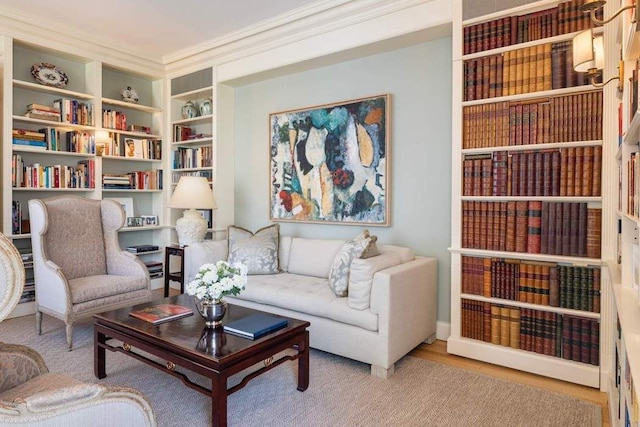 sitting room featuring built in shelves, crown molding, and wood finished floors