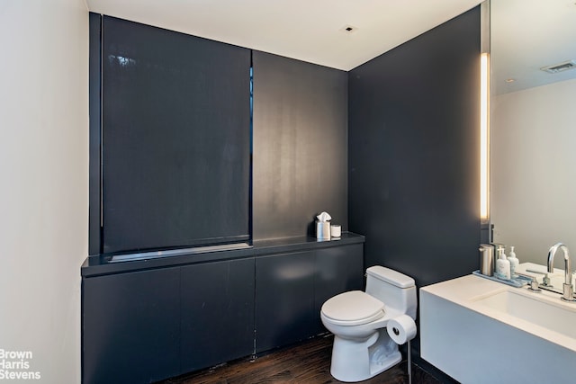 bathroom featuring toilet, vanity, wood finished floors, and visible vents