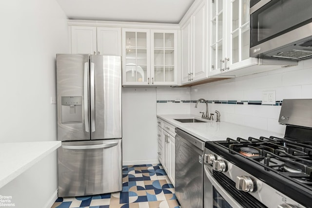 kitchen with stainless steel appliances, white cabinetry, sink, and tasteful backsplash