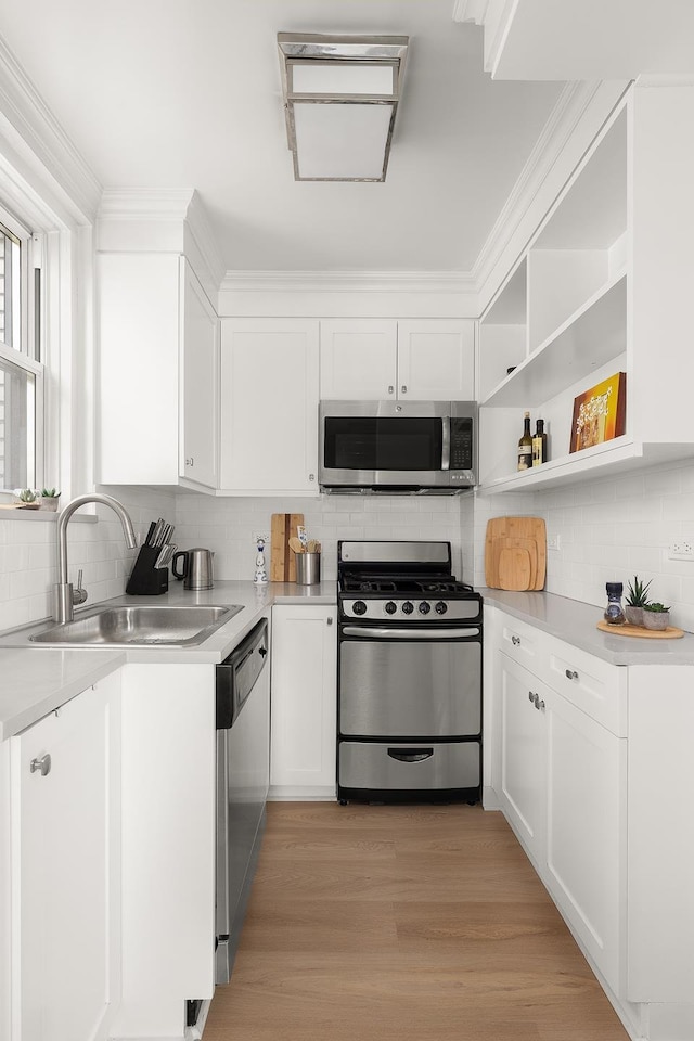 kitchen with white cabinetry, appliances with stainless steel finishes, light countertops, and a sink