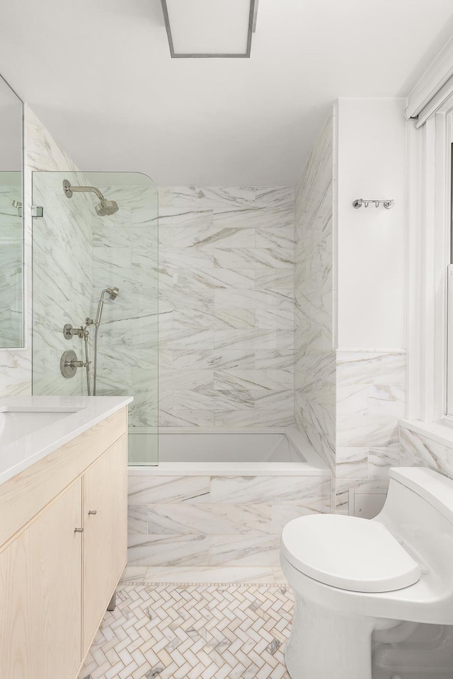 bathroom with tile walls, a marble finish shower, vanity, and toilet