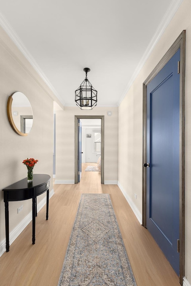 corridor featuring baseboards, light wood-style flooring, and crown molding