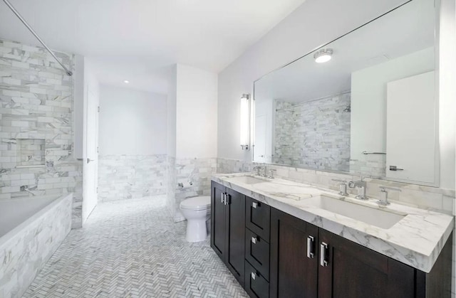 full bathroom with tiled shower / bath, tile walls, vanity, and toilet