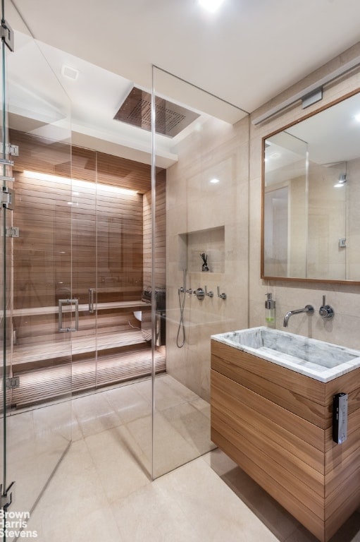 bathroom with tile patterned floors, tile walls, a shower with shower door, and vanity