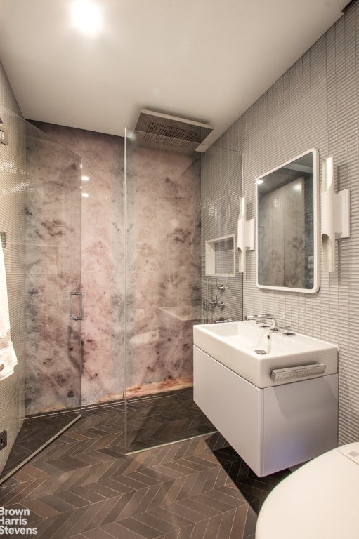 bathroom with tile walls, walk in shower, and vanity