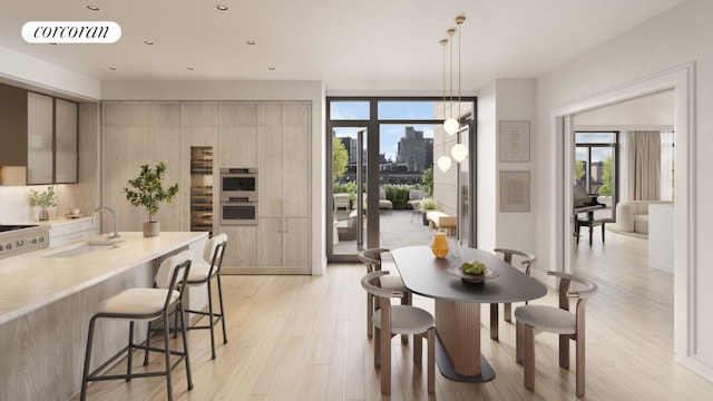 dining space featuring sink, light wood-type flooring, and a wall of windows