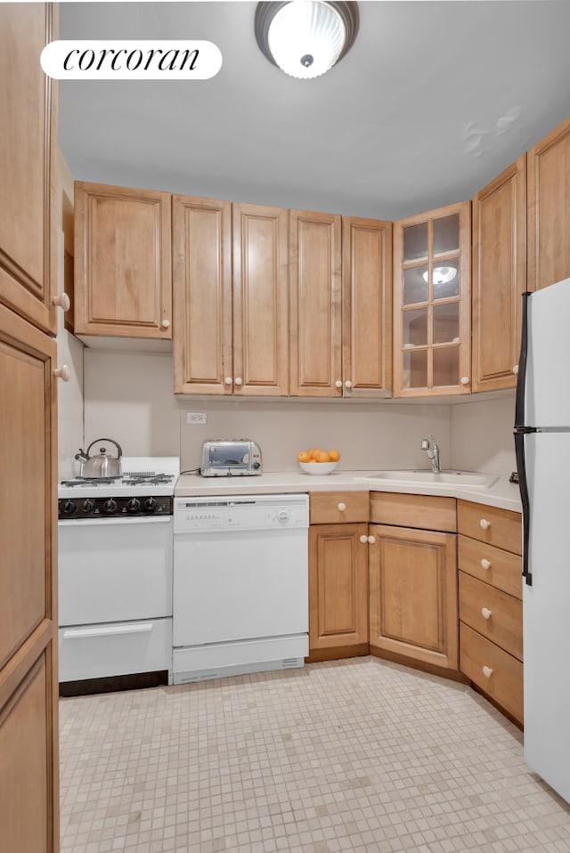 kitchen with white appliances, glass insert cabinets, light countertops, and a sink