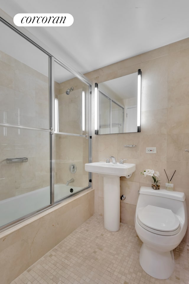 full bathroom featuring tiled shower / bath, a sink, toilet, and tile walls