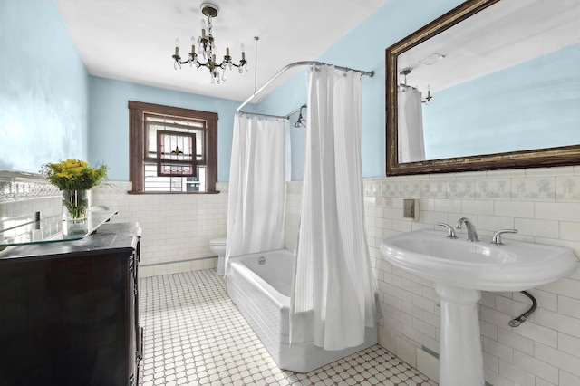 bathroom with tile patterned floors, toilet, tile walls, and a wainscoted wall