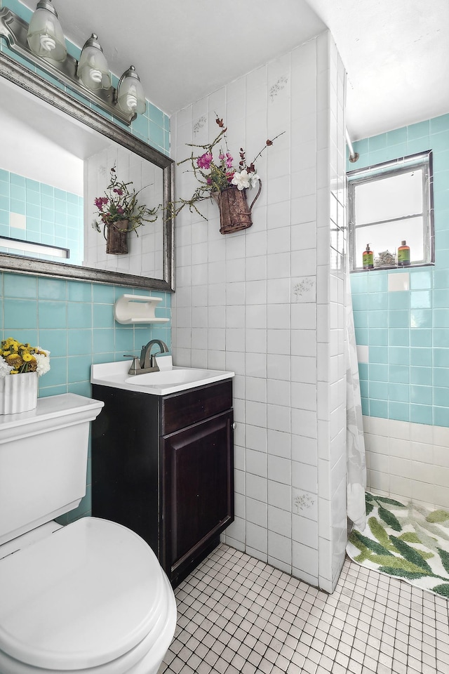 bathroom featuring a tile shower, toilet, tile walls, and vanity