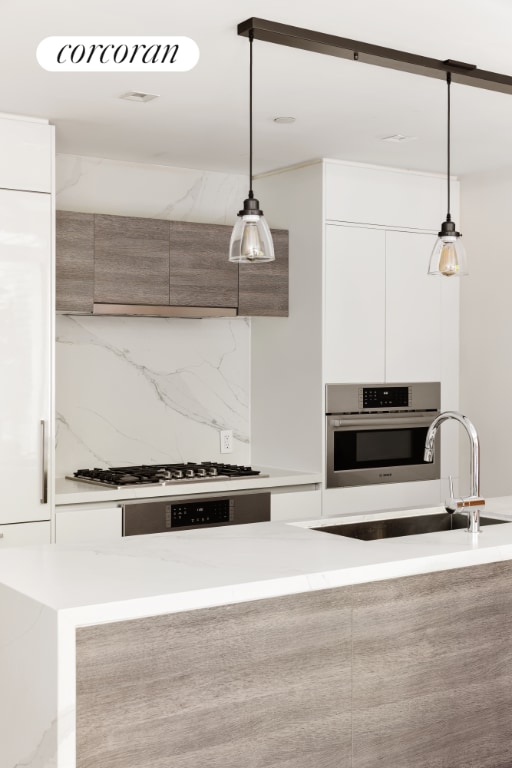 kitchen featuring decorative light fixtures, gas cooktop, white cabinetry, and oven