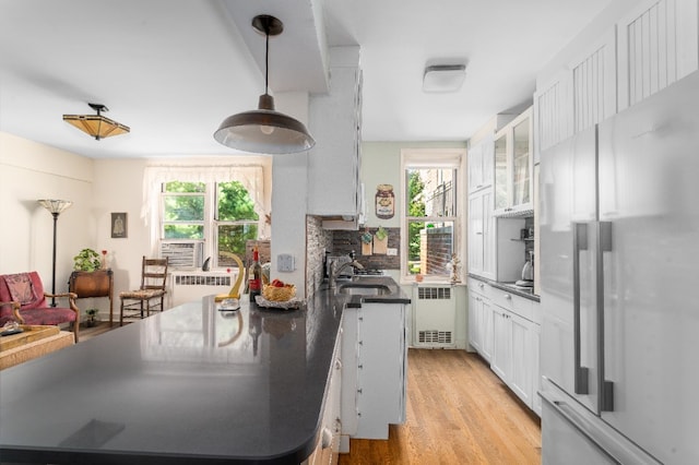 kitchen featuring a sink, white cabinets, light wood-style floors, freestanding refrigerator, and radiator