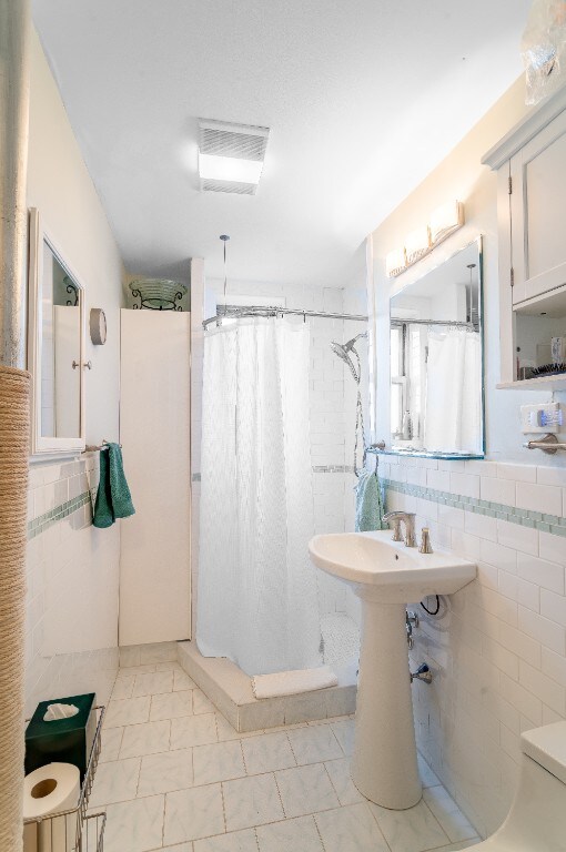5650 Netherland Ave Unit 1A, New York City, NY 10471 - bathroom with a shower with curtain, tile walls, and visible vents