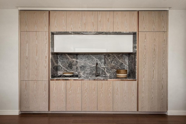 interior details with wet bar, a sink, baseboards, and wood finished floors